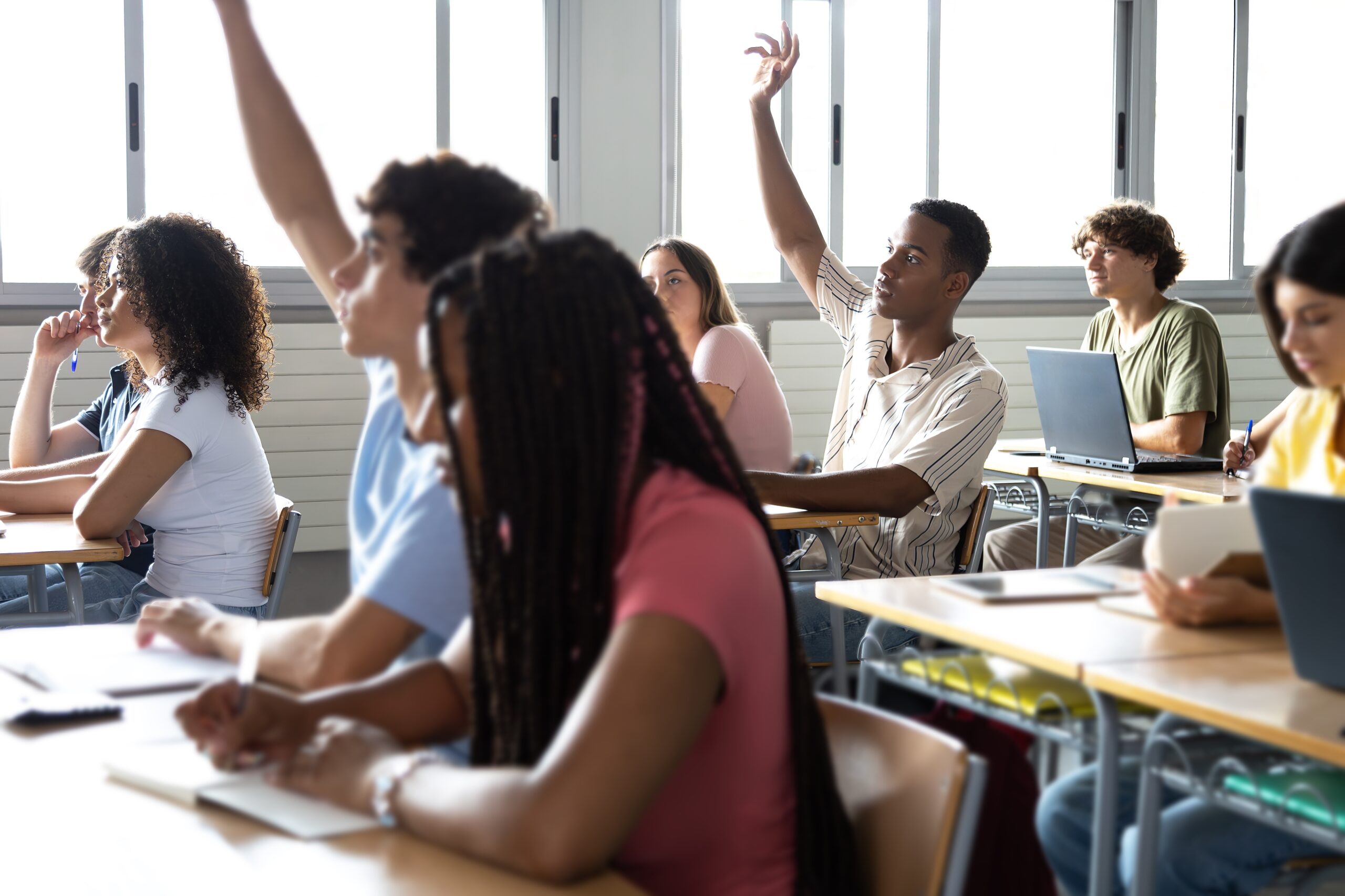 Teen,Males,Raising,Hand,To,Ask,Question,About,Lesson,In Teen males raising hand to ask question about lesson in classroom.Group of multiracial high school teenage students in class. Education concept.